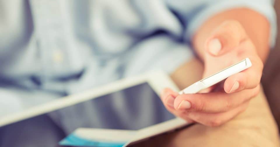Person holding smartphone and tablet, focusing on digital devices.