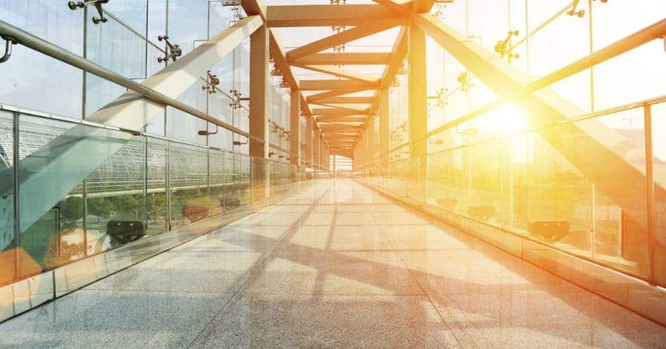 Bright glass corridor with sunlight streaming through, modern architecture design.