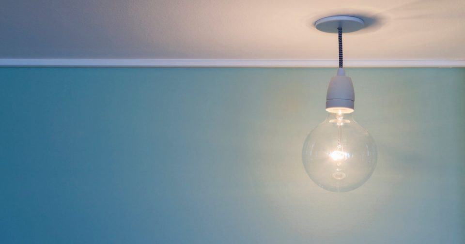 Simple hanging light bulb on a blue ceiling for modern interior design.