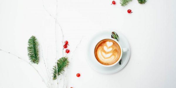 Cup of coffee with heart-shaped latte art on a white surface.