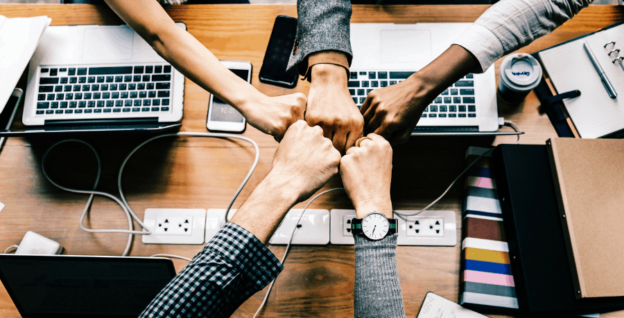 a group of people fist bumping as a metaphor for the fact that in concurrent planning every part of the chain has to work together and taken into consideration simultaneously.